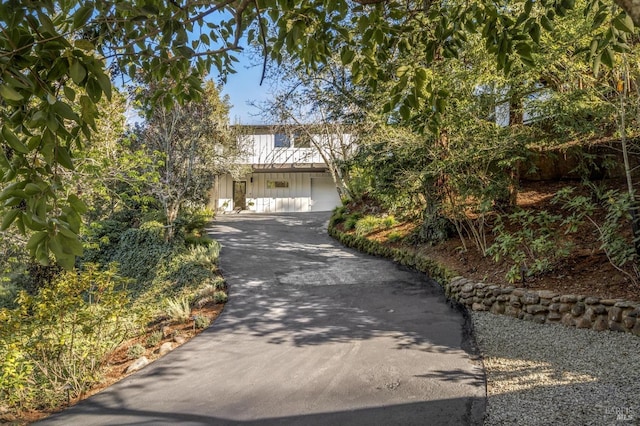 view of property hidden behind natural elements featuring concrete driveway