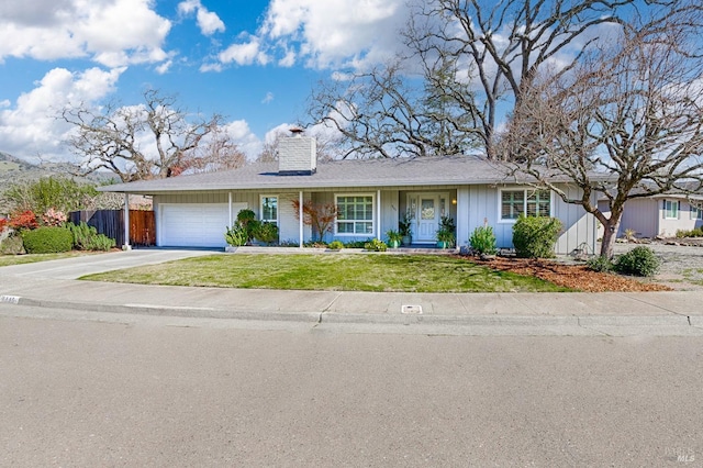 view of front of house featuring a chimney, concrete driveway, a front yard, fence, and a garage