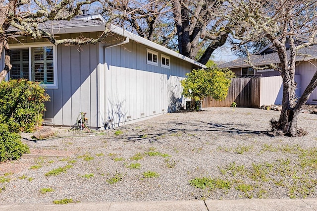 view of side of property featuring gravel driveway and fence