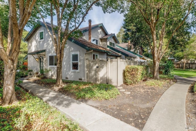 view of side of property with crawl space, fence, and stucco siding