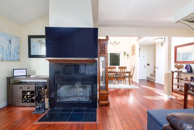 living area with wood-type flooring, baseboards, vaulted ceiling, and a tile fireplace