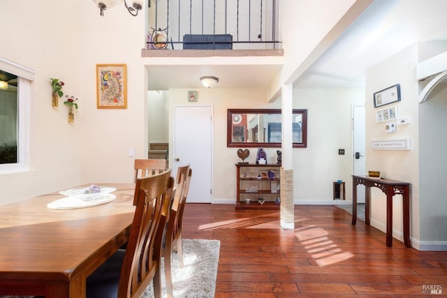 dining room with a high ceiling, hardwood / wood-style floors, and baseboards