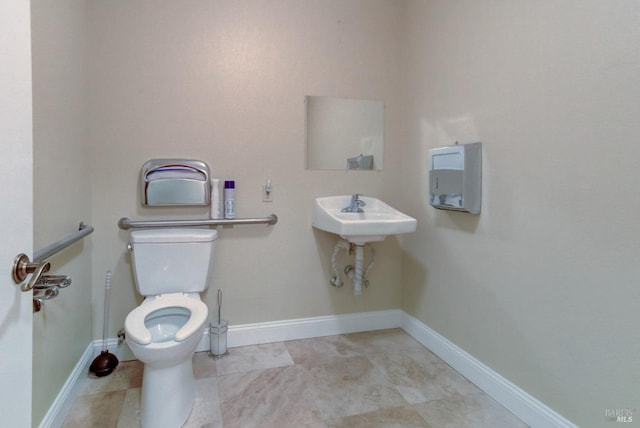 half bathroom with a sink, toilet, and baseboards