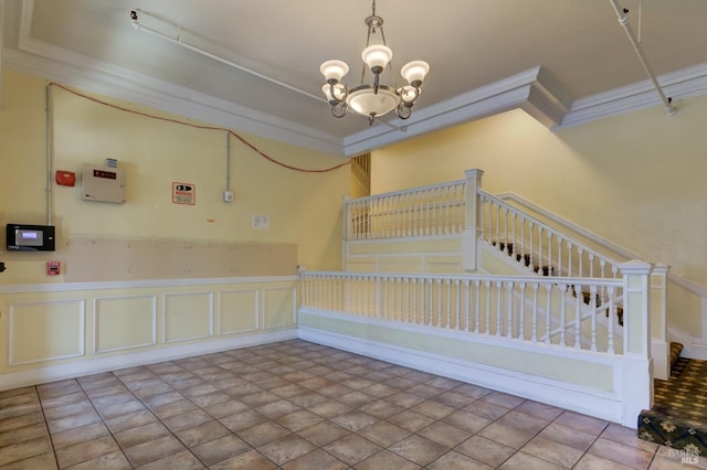 unfurnished room with ornamental molding, a chandelier, wainscoting, and stairs