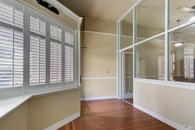 hall featuring a healthy amount of sunlight, baseboards, and wood finished floors