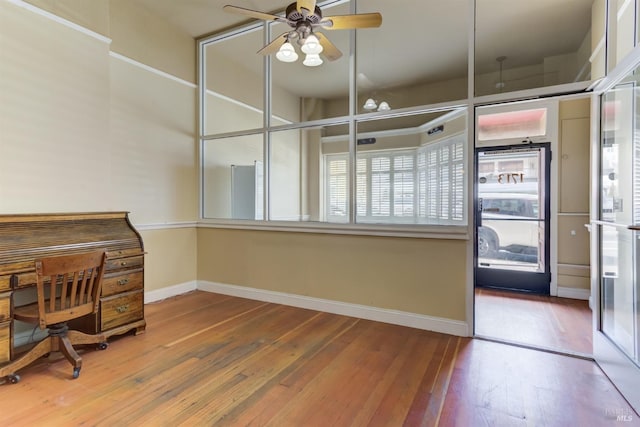 unfurnished office featuring hardwood / wood-style floors, a ceiling fan, and baseboards