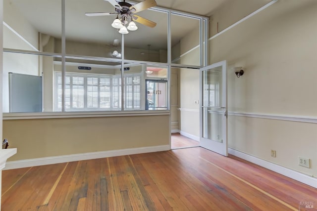 empty room featuring a ceiling fan, baseboards, and hardwood / wood-style flooring