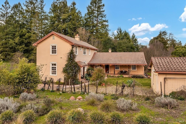 mediterranean / spanish house with a tile roof, a chimney, a patio, and stucco siding