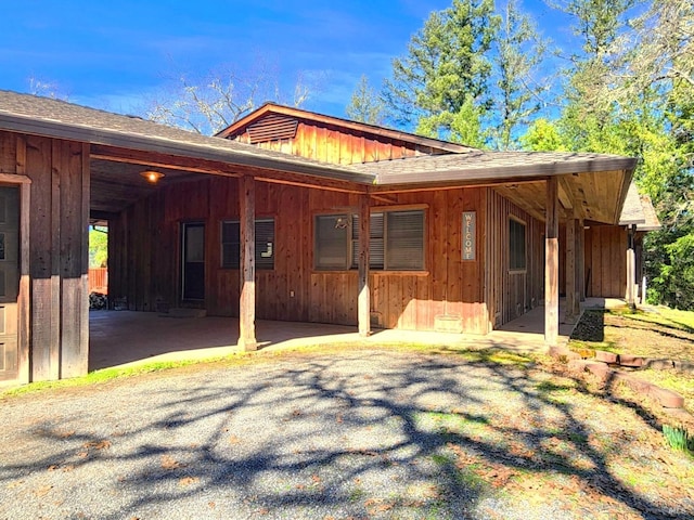 exterior space with an attached carport and a shingled roof