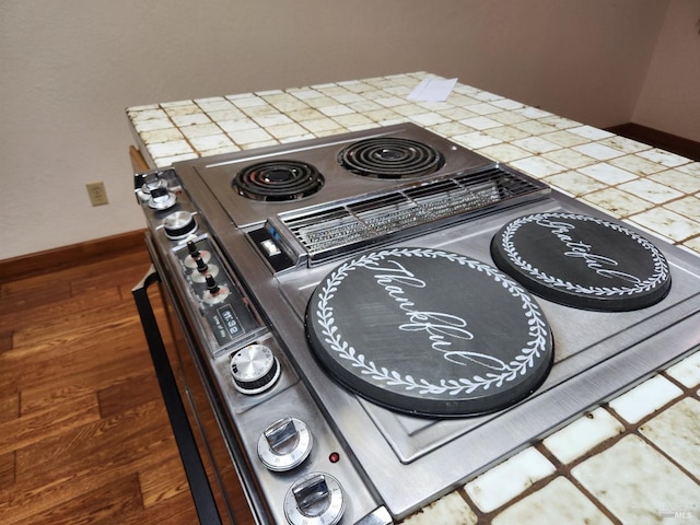 room details with baseboards, tile counters, wood finished floors, and electric stove