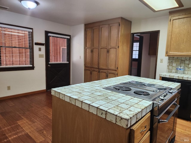 kitchen with range with two ovens, tile counters, decorative backsplash, wood finished floors, and baseboards