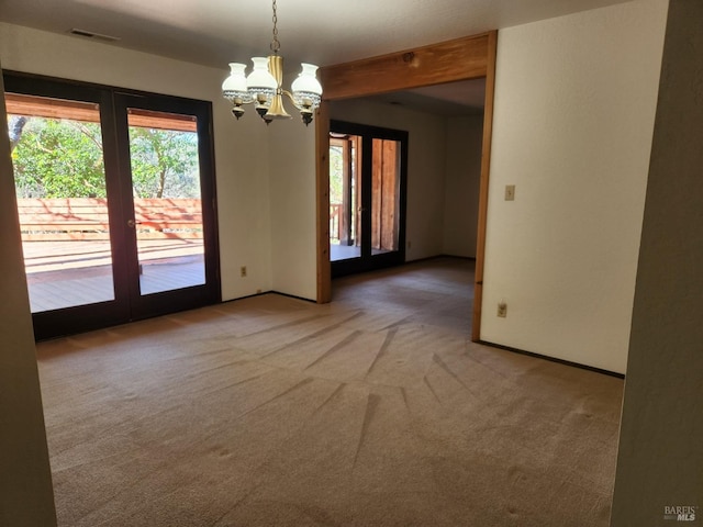 unfurnished room featuring a healthy amount of sunlight, visible vents, a chandelier, and carpet flooring