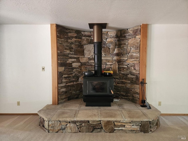 details with a textured ceiling, carpet floors, a wood stove, and baseboards