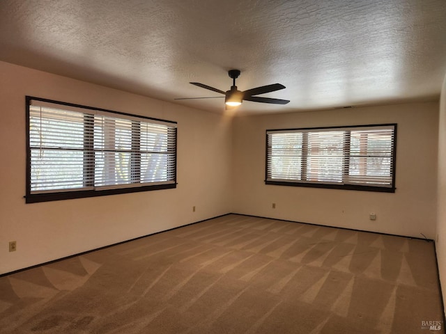 unfurnished room with carpet floors, a textured ceiling, a ceiling fan, and a wealth of natural light