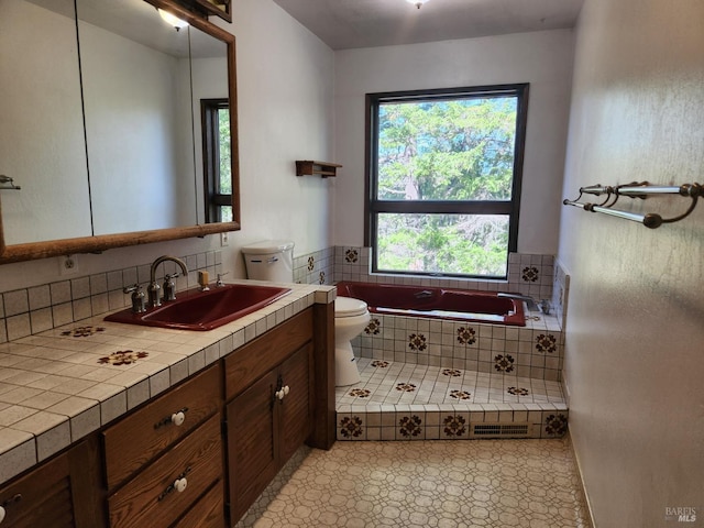 bathroom featuring toilet, a relaxing tiled tub, visible vents, vanity, and tile patterned floors