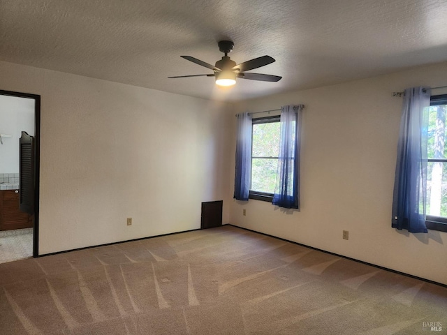 carpeted spare room featuring a ceiling fan and a textured ceiling