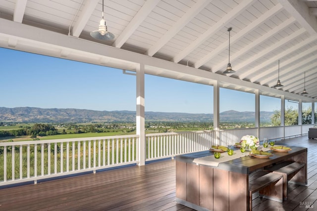 deck featuring a mountain view, a ceiling fan, and outdoor dining space
