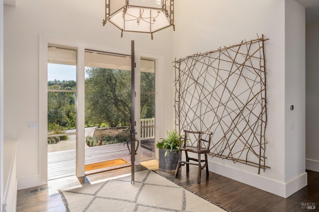 living area featuring an inviting chandelier, visible vents, wood finished floors, and baseboards