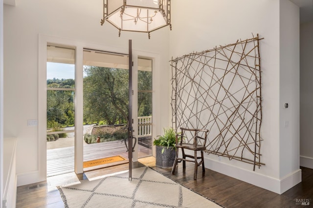 doorway with visible vents, baseboards, wood finished floors, and an inviting chandelier