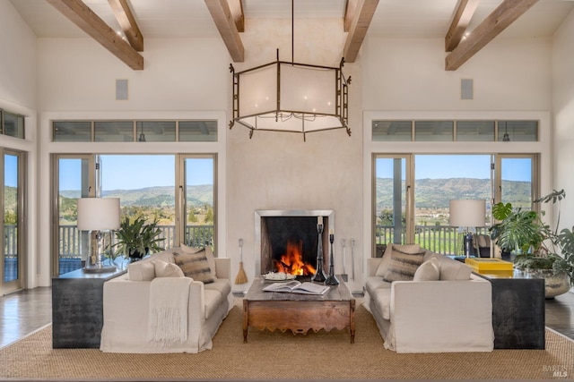 living room with beamed ceiling, a mountain view, a lit fireplace, and wood finished floors