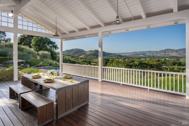 deck with a mountain view and outdoor dining area