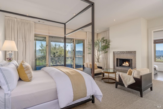 bedroom featuring access to exterior, multiple windows, recessed lighting, and a lit fireplace