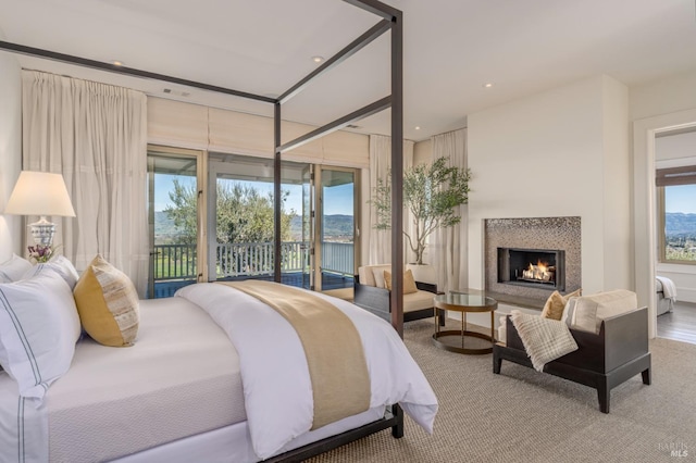 bedroom with access to exterior and a lit fireplace
