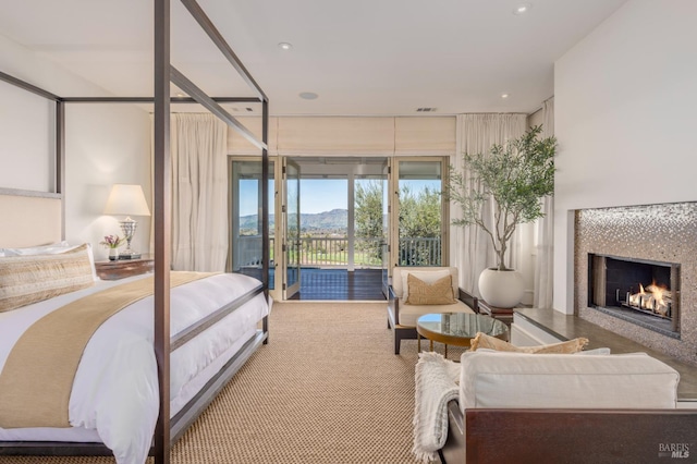 carpeted bedroom featuring recessed lighting, a mountain view, a warm lit fireplace, and access to exterior