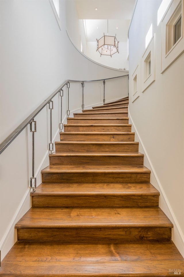 staircase with wood finished floors and a towering ceiling