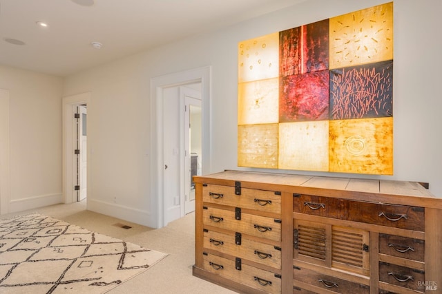 hall featuring visible vents, baseboards, and light colored carpet