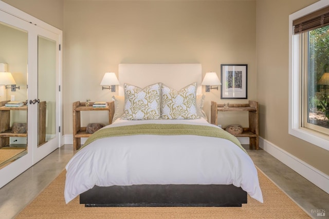 bedroom with french doors, baseboards, and finished concrete floors