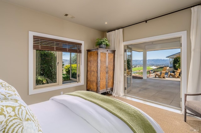 bedroom with multiple windows, visible vents, a mountain view, and access to exterior