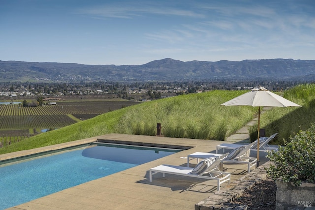 view of pool featuring fence, a patio area, a fenced in pool, and a mountain view