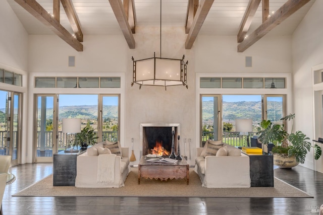 living room with hardwood / wood-style floors, a high ceiling, a mountain view, and a warm lit fireplace