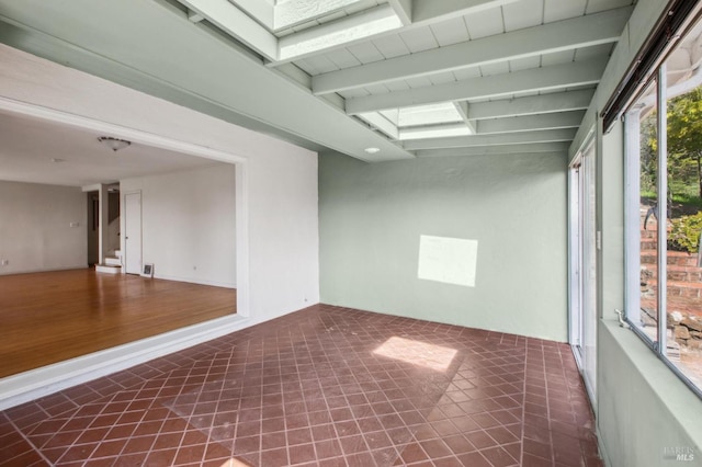 empty room featuring beamed ceiling and a skylight