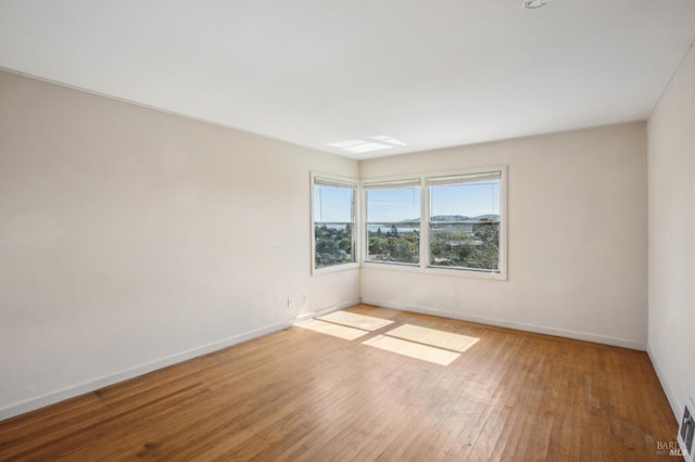 spare room featuring visible vents, baseboards, and wood finished floors