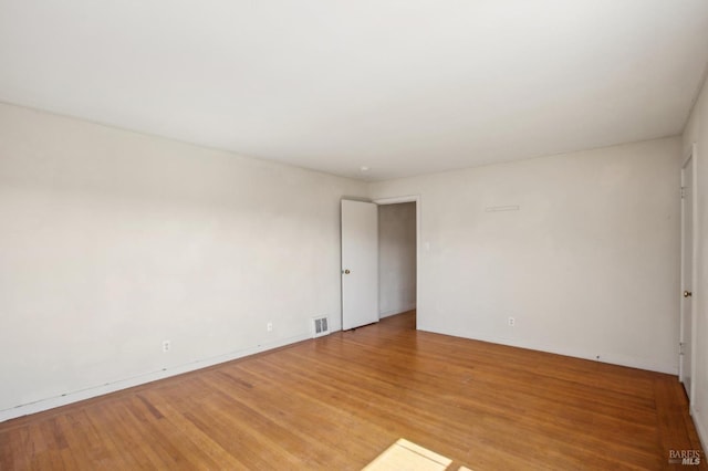 spare room with visible vents, light wood-style flooring, and baseboards