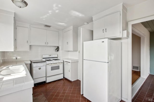 kitchen featuring white cabinetry, white appliances, tile counters, and visible vents