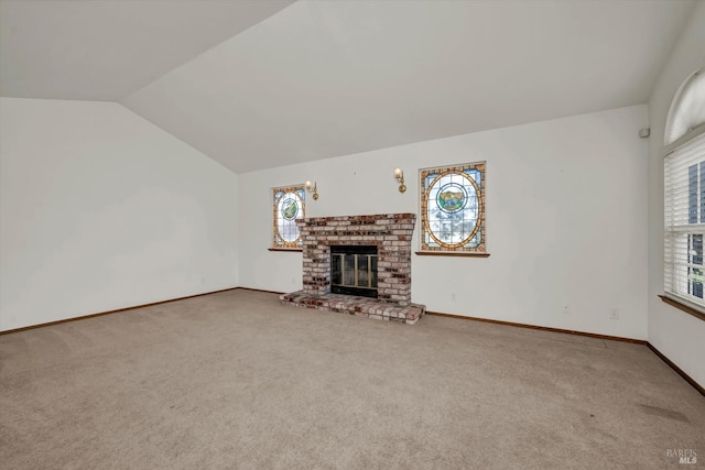 unfurnished living room with plenty of natural light, a fireplace, vaulted ceiling, and carpet flooring