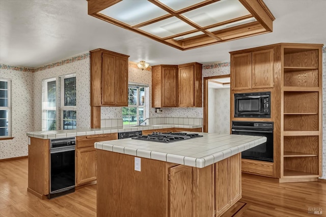 kitchen with wallpapered walls, light wood finished floors, a kitchen island, black appliances, and open shelves