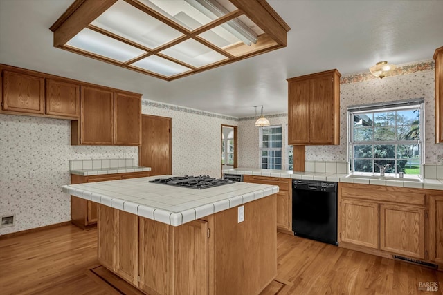 kitchen featuring dishwasher, light wood-type flooring, gas stovetop, and wallpapered walls