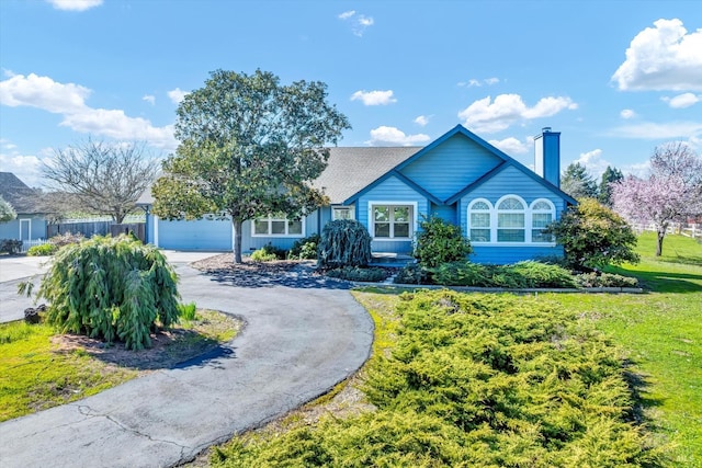 view of front of property featuring aphalt driveway, a front lawn, a chimney, and an attached garage