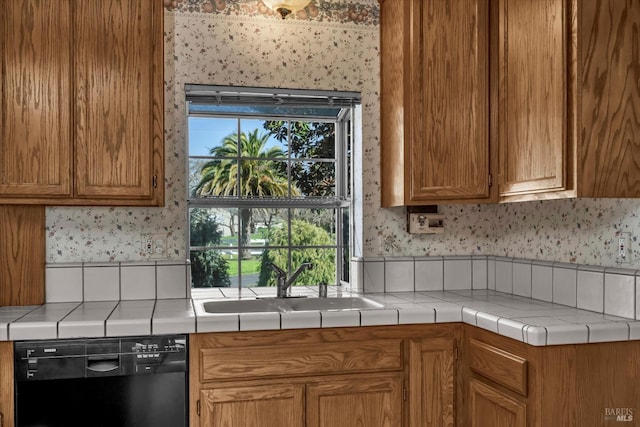 kitchen featuring black dishwasher, brown cabinets, a sink, and wallpapered walls