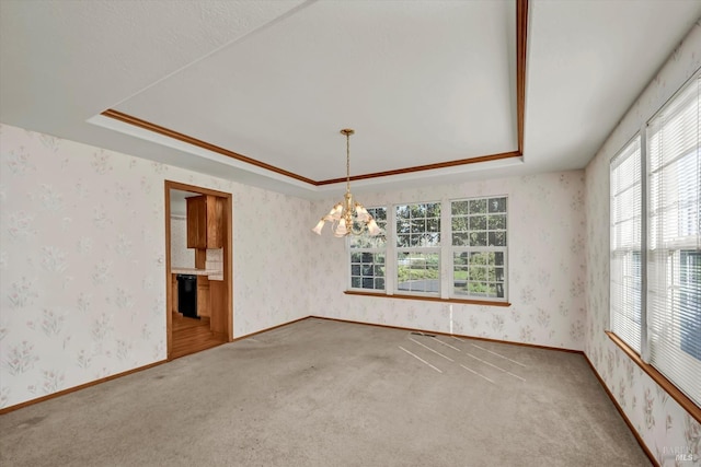 carpeted empty room with a tray ceiling, an inviting chandelier, and wallpapered walls