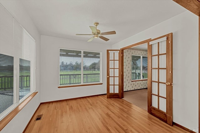 empty room featuring ceiling fan, wood finished floors, visible vents, baseboards, and french doors