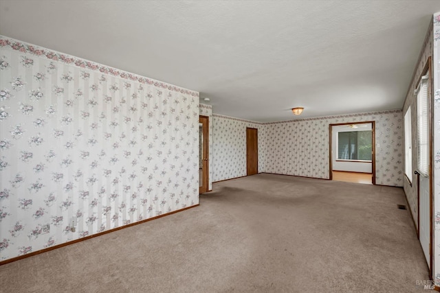 spare room featuring wallpapered walls, a textured ceiling, and carpet flooring