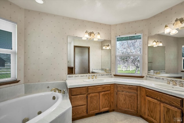 bathroom featuring a sink, a tub with jets, and wallpapered walls