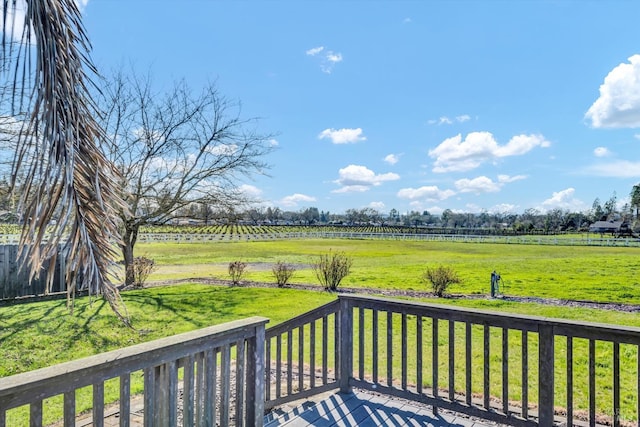 wooden deck with a rural view and a lawn