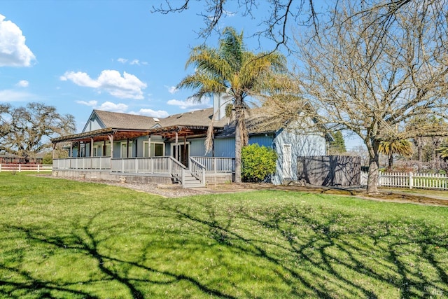 rear view of property with fence and a lawn