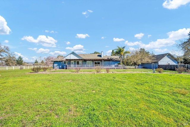 rear view of house featuring fence and a lawn